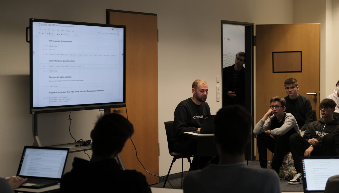 Data Scientist Johannes Häfner explaining programming to an audience on a computer.