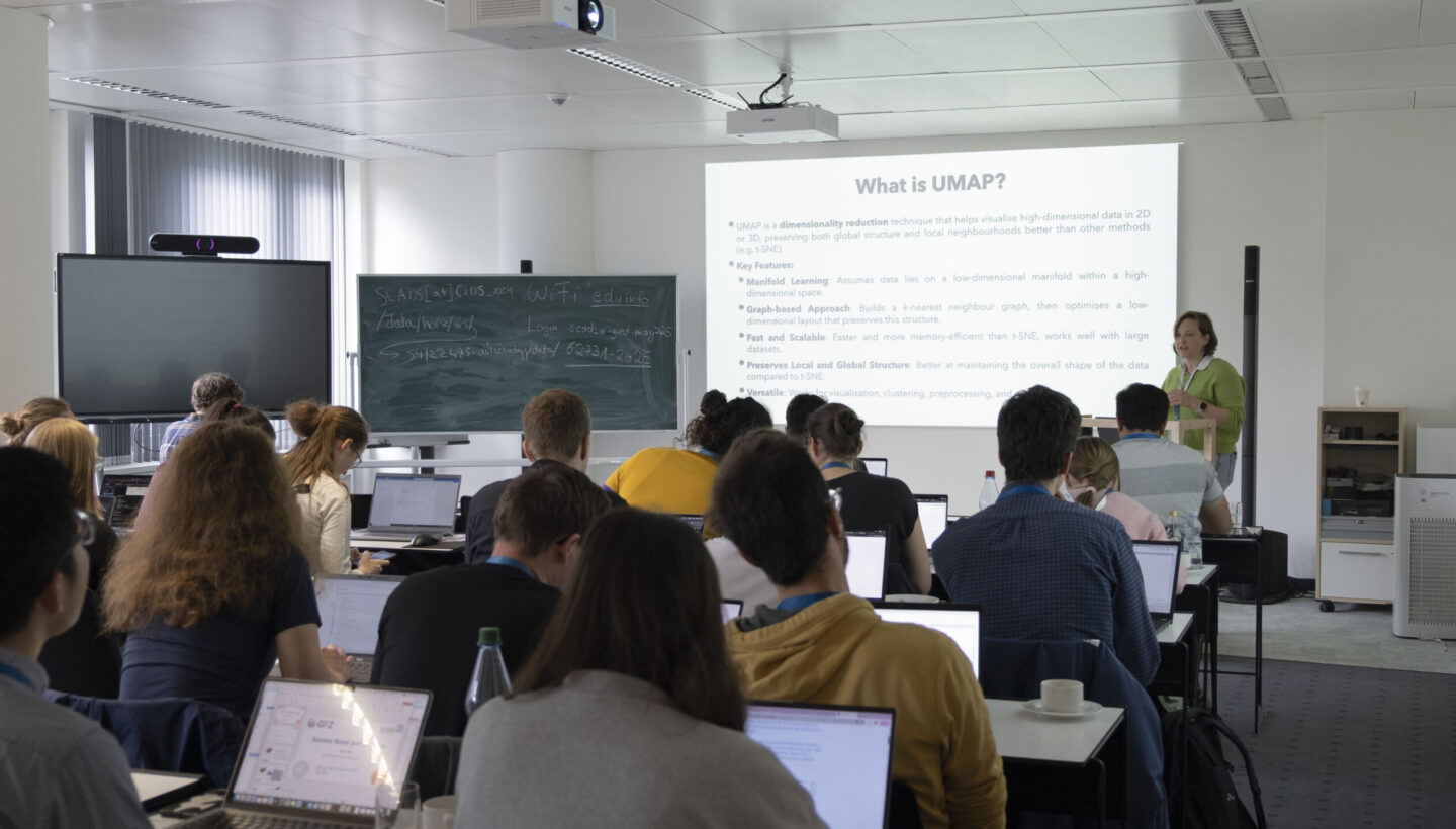 In a vibrant living lab, Dr. Maria Tsekhmistrenko energetically presents an introduction to UMAP. The room buzzes with engaged participants, including researchers and students, all immersed in the interactive session.