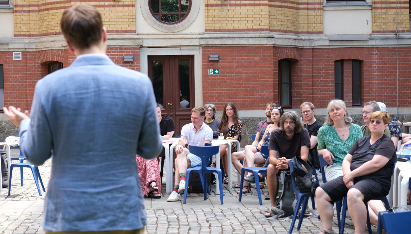 Photo. Niklas Deckers talking to the participants of KI Frühstück 2023.