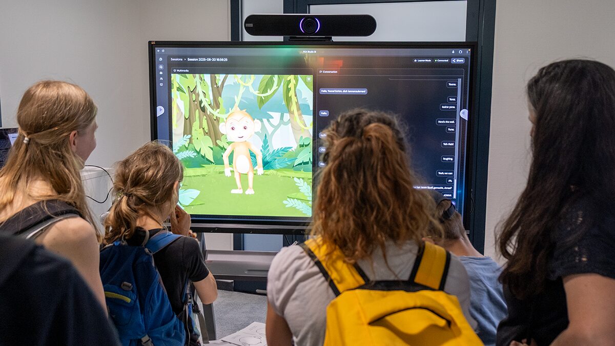 Photo. Visitors stand in front of a screen to interact with Uku, the digital monkey.