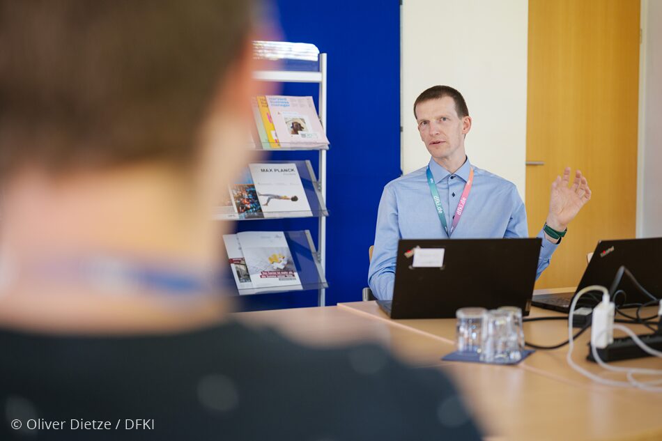 Photo. Dr. Frank Loebe is in a discussion with a participant of the workshop "Forum on Promoting, Training and Managing Doctoral Candidates". © Oliver Dietze / DFKI