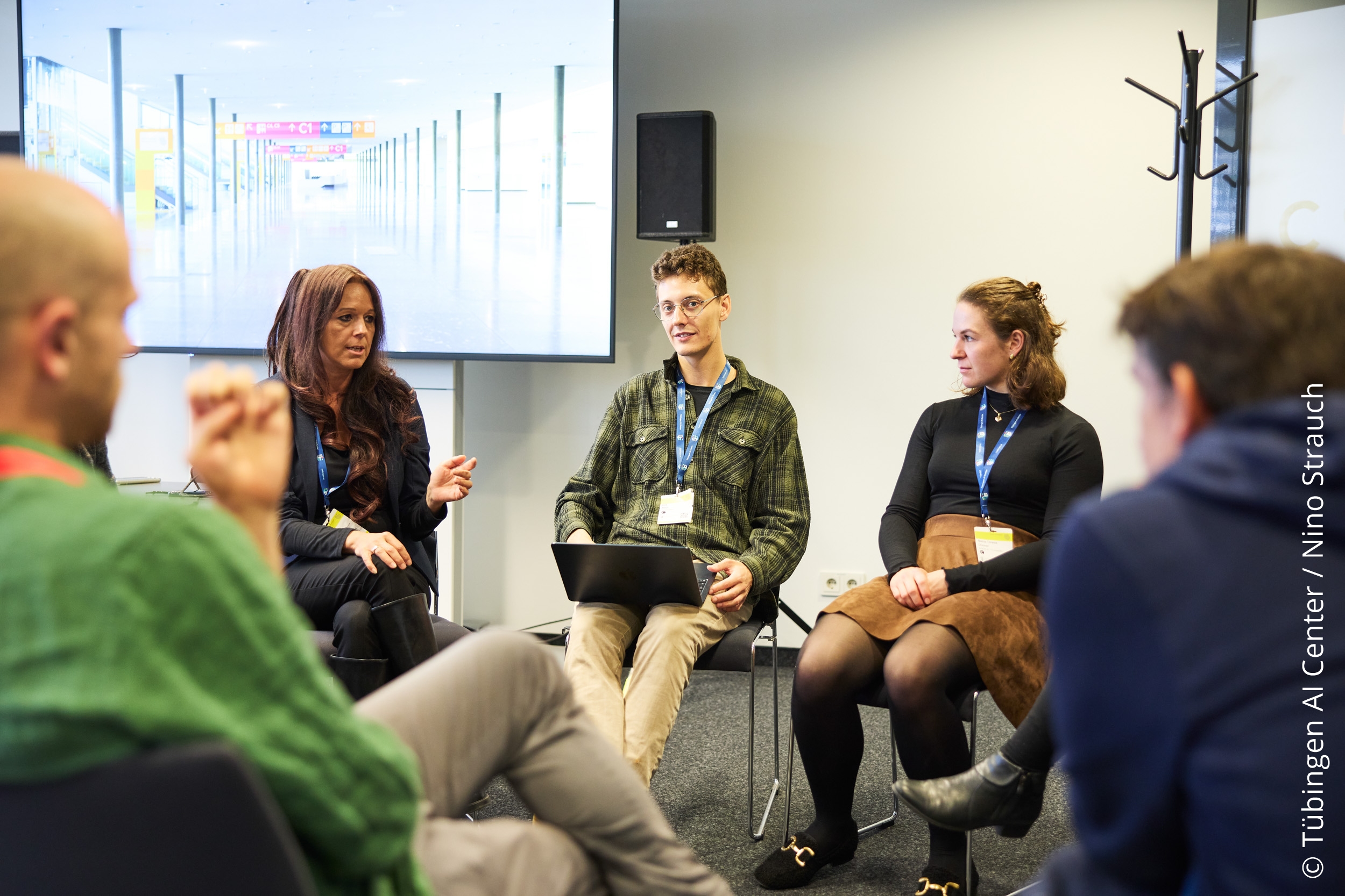 Photo. Dr. Sandra Hummel, Erik Marx, and Mana-Teresa Donner are in discussion with the participants of the workshop "AI in Education". © Tübingen AI Center / Nino Strauch