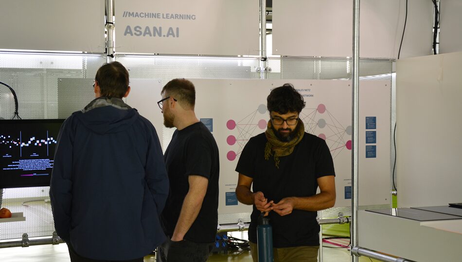 Photo. People having a look at the asanAI exhibit at the exhibition DataSpaces. © Carolin Alice Schenk