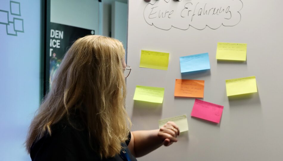 Photo. Dr. Claudia Loitsch is reading colourful notes on which the participants have summarized their experiences with chatbots.