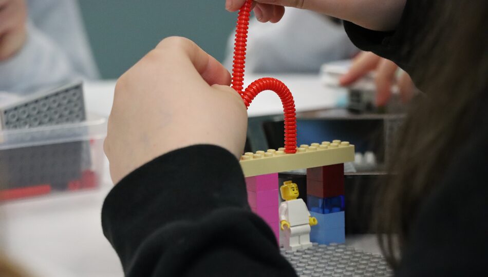 Photo. A girl builds a machine that would make her life easier with colourful building blocks.