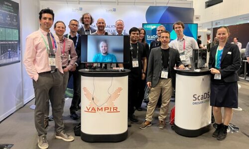 Photo. Our team members photographed in front of the ScaDS.AI Dresden/Leipzig booth at ISC 2025.
