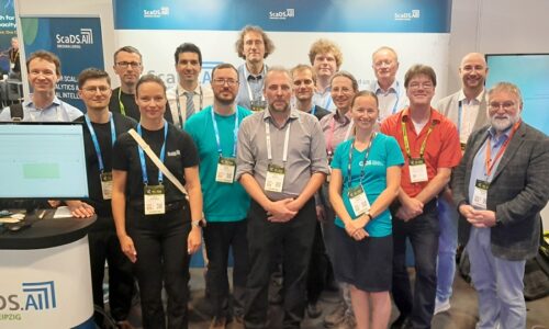 Photo. The team of ScaDS.AI Dresden/Leipzig and ZIH photographed together in front of the booth of ScaDS.AI Dresden/Leipzig at ISC High Performance 2026.