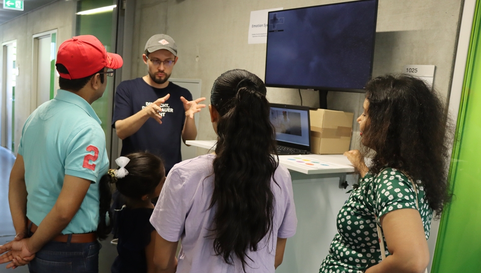 Photo. Andrei Politov is presenting the demonstrator "Emotion Symphony" to 4 visitors at Andreas Pfitzmann Bau in Dresden.