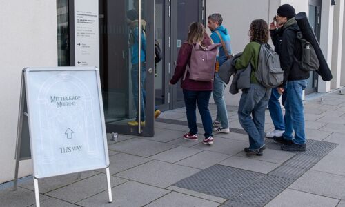 Photo. People entering a door to the building where the Mittelerde Meeting 2025 takes place.