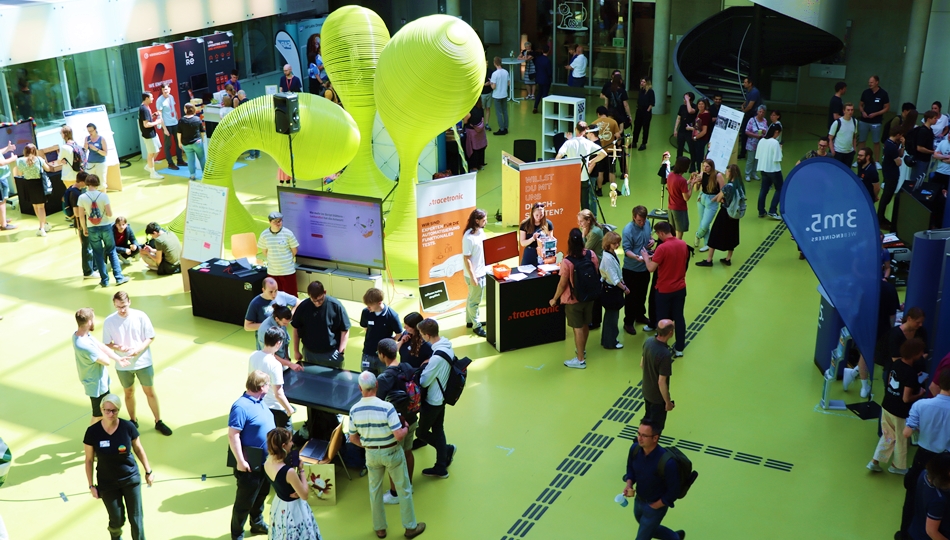 Photo. The foyer of Andreas-Pfitzmann-Bau at TU Dresden is packed with visitors during OUTPUT.DD 2025.