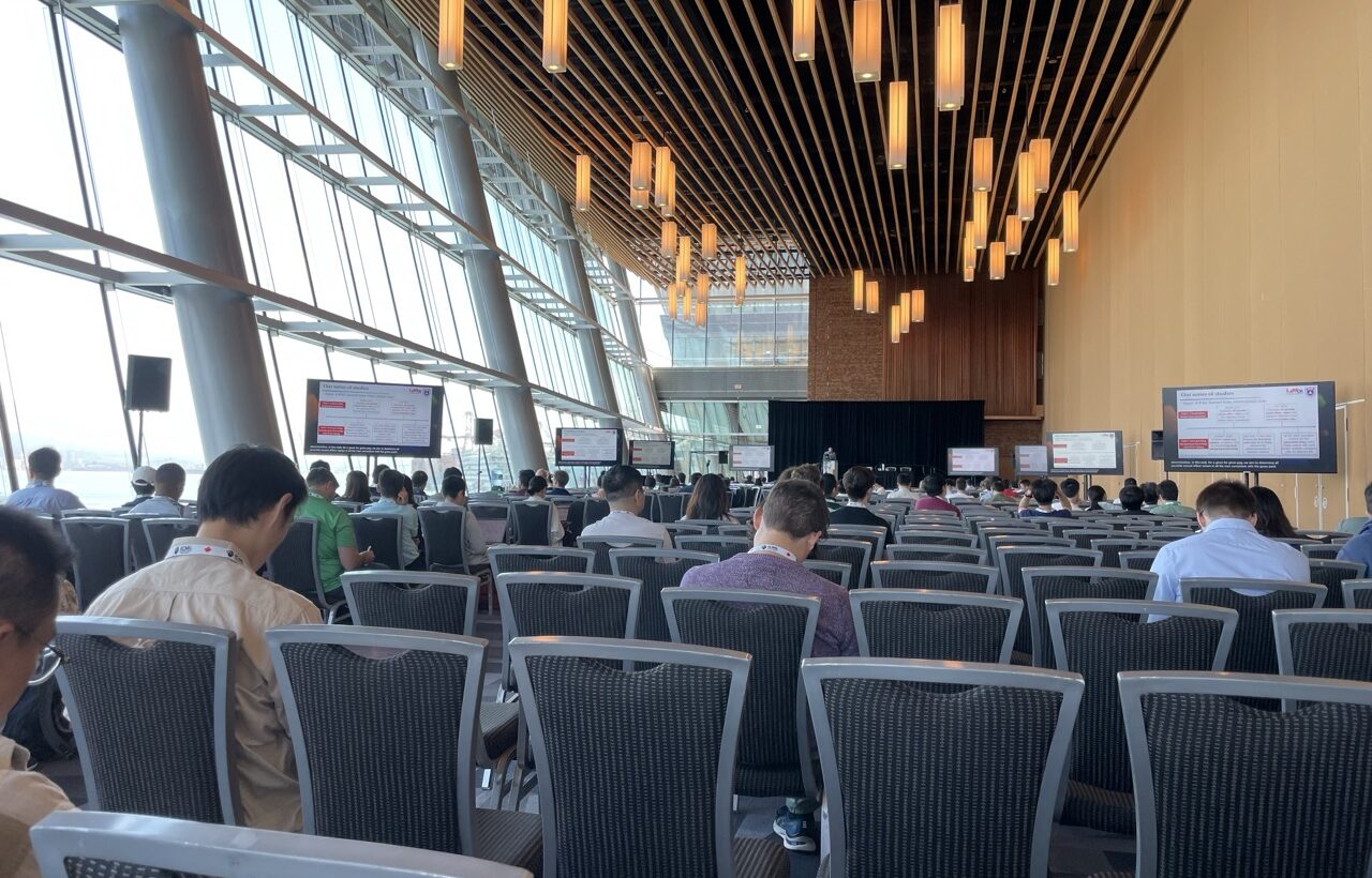 Photo. Listeners waiting for a lecture to begin.